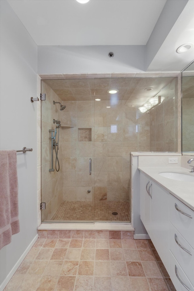 bathroom featuring vanity, baseboards, and a stall shower