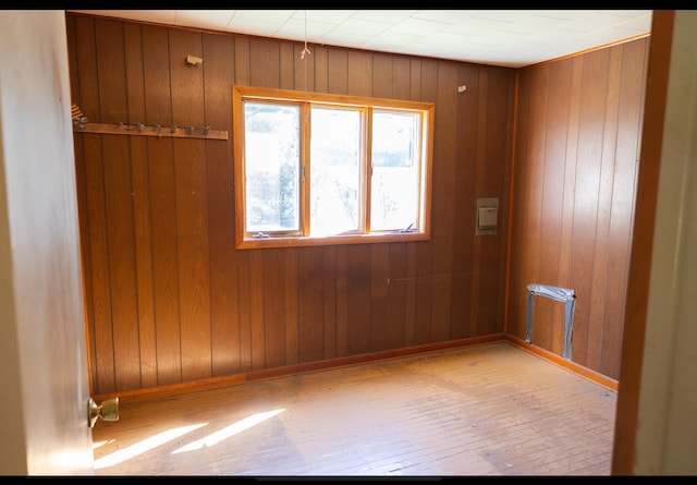spare room featuring baseboards, wood walls, and hardwood / wood-style flooring
