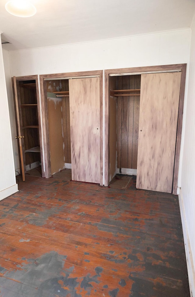 unfurnished bedroom with two closets and hardwood / wood-style floors