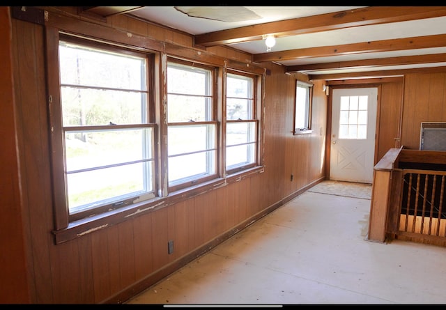 spare room with wood walls and beam ceiling