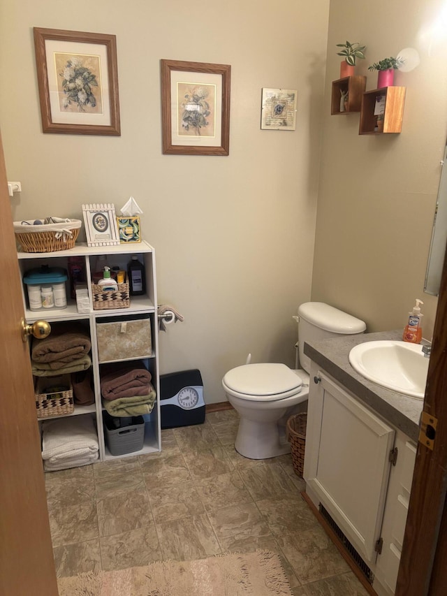 bathroom featuring toilet, stone finish flooring, and vanity