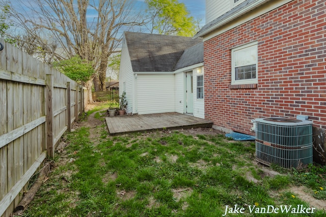 exterior space with fence private yard, a wooden deck, brick siding, and cooling unit
