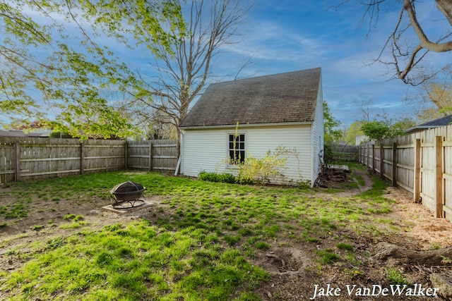 view of outdoor structure featuring a fenced backyard and an outdoor fire pit