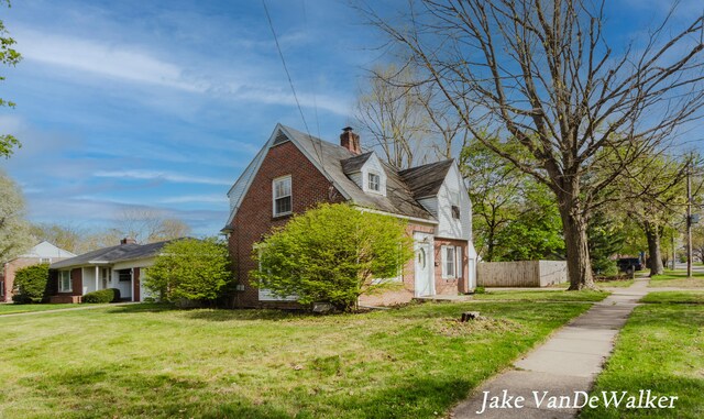 view of property exterior with a yard, brick siding, fence, and a chimney