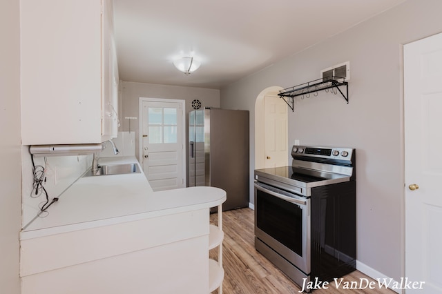kitchen with light wood-style floors, a sink, light countertops, and stainless steel appliances