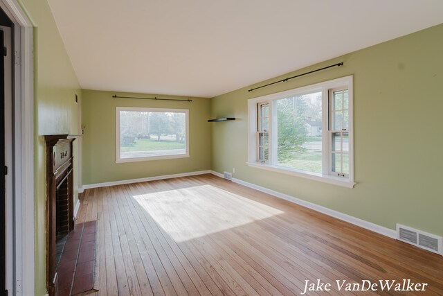unfurnished living room featuring visible vents, wood-type flooring, and baseboards