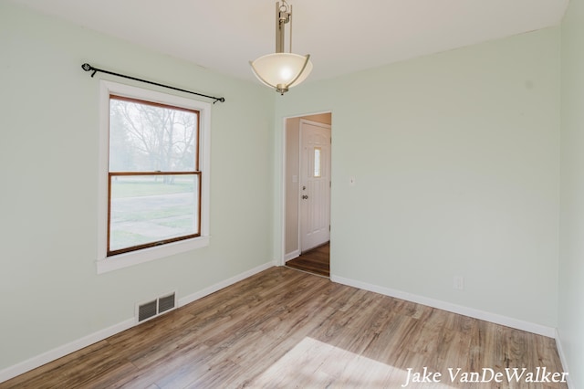 spare room featuring visible vents, baseboards, and wood finished floors