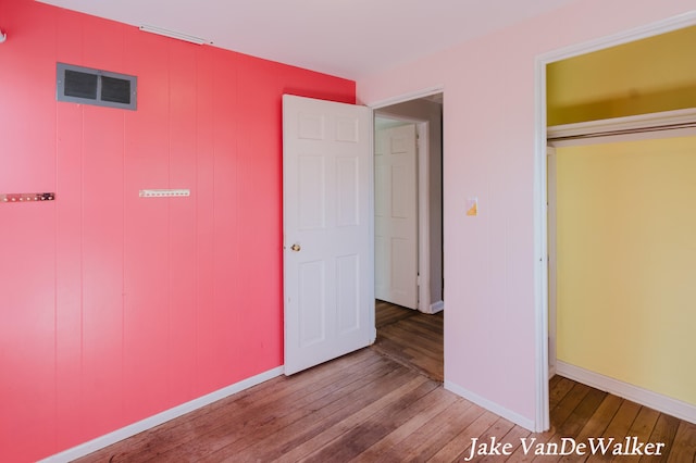 unfurnished bedroom with baseboards, visible vents, and hardwood / wood-style floors