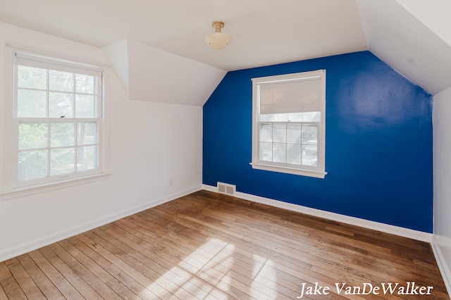 bonus room with vaulted ceiling, a healthy amount of sunlight, and hardwood / wood-style flooring
