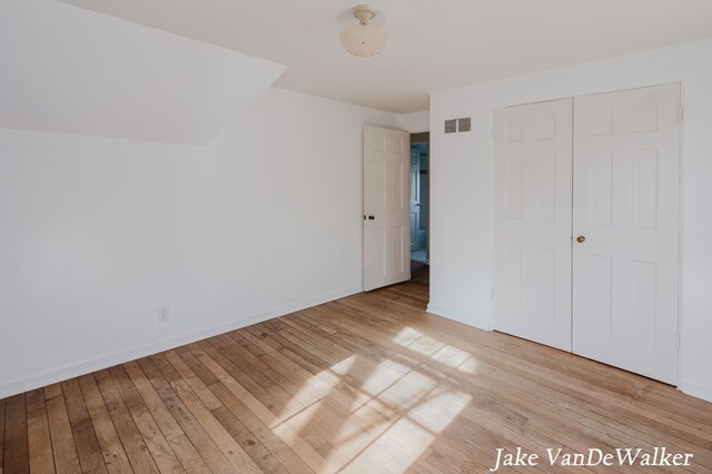unfurnished bedroom with baseboards, a closet, light wood-style flooring, and visible vents