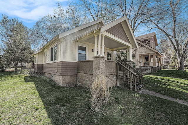 view of property exterior with covered porch, a lawn, and stairway