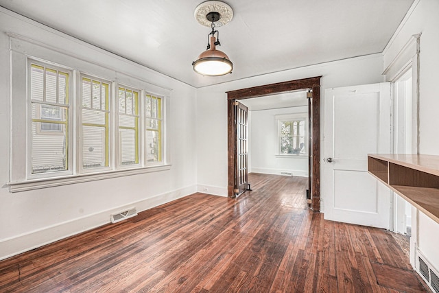 unfurnished dining area featuring baseboards, dark wood finished floors, and visible vents