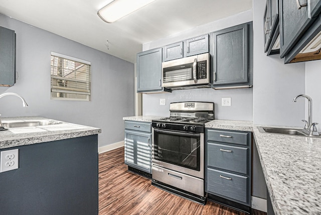 kitchen with appliances with stainless steel finishes, a sink, and dark wood-type flooring