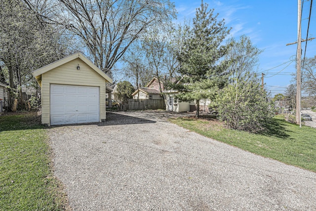 detached garage featuring fence and driveway