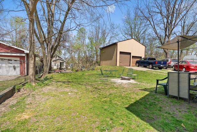 view of yard with fence, a fire pit, an outdoor structure, and a garage