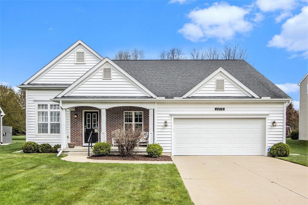 view of front facade featuring roof with shingles, an attached garage, driveway, and a front yard