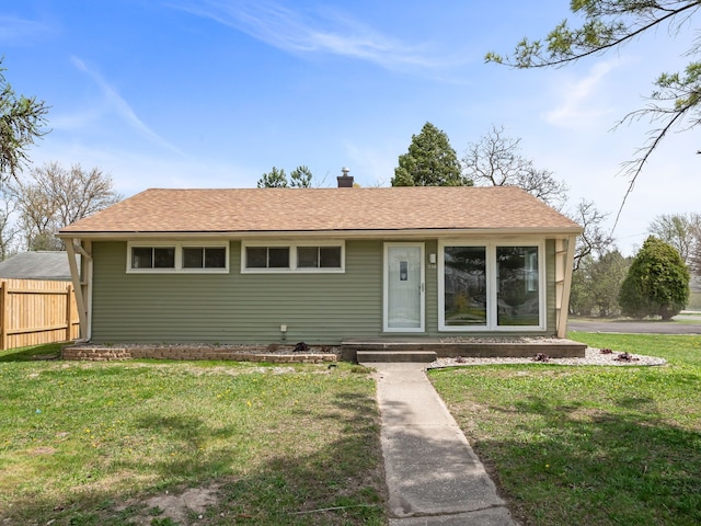 ranch-style house with a shingled roof, a front lawn, fence, and a chimney