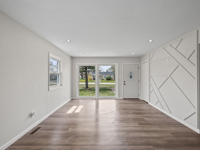 interior space featuring baseboards, recessed lighting, wood finished floors, and visible vents