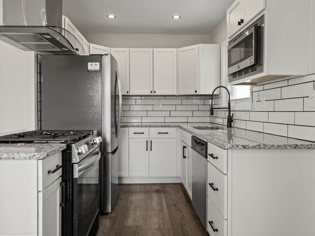 kitchen with white cabinets, a sink, dark wood finished floors, stainless steel appliances, and range hood