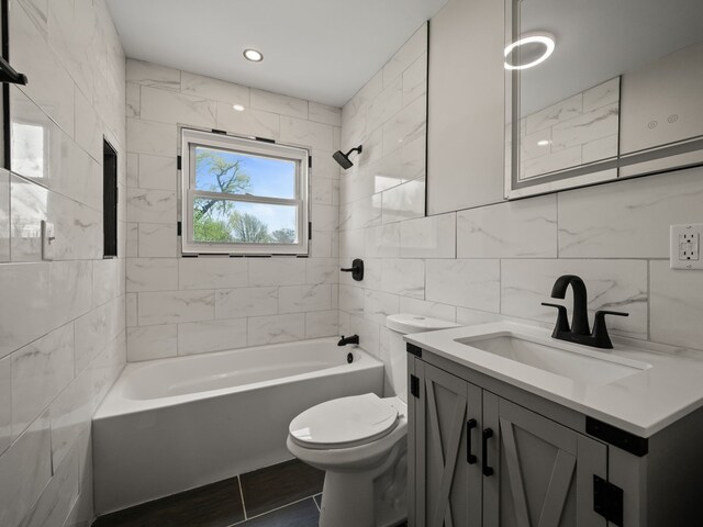 full bath featuring tile patterned flooring, vanity, toilet, shower / bath combination, and tile walls