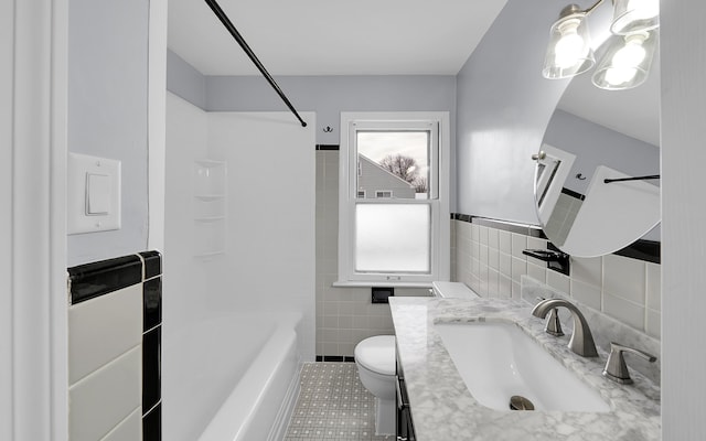 full bathroom with tile walls, toilet, tile patterned flooring, vanity, and shower / bathtub combination