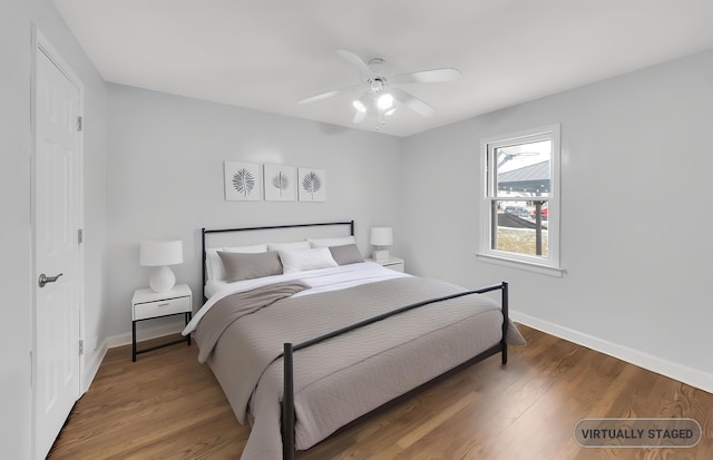bedroom featuring baseboards, wood finished floors, and a ceiling fan