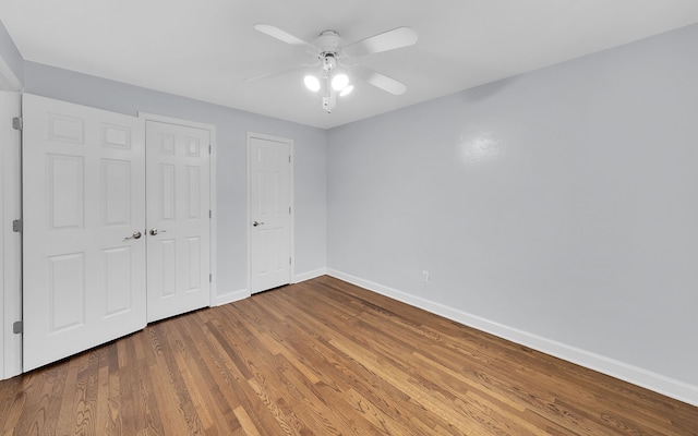 unfurnished bedroom featuring baseboards, wood finished floors, ceiling fan, and a closet