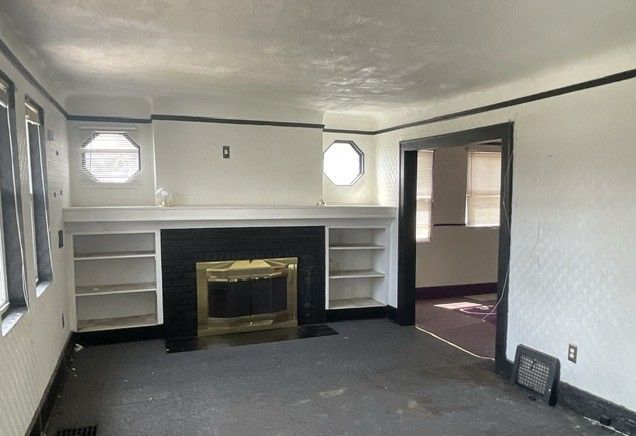 16837 Winthrop St, Detroit, MI 48235 - unfurnished living room with a textured ceiling, baseboards, and built in features