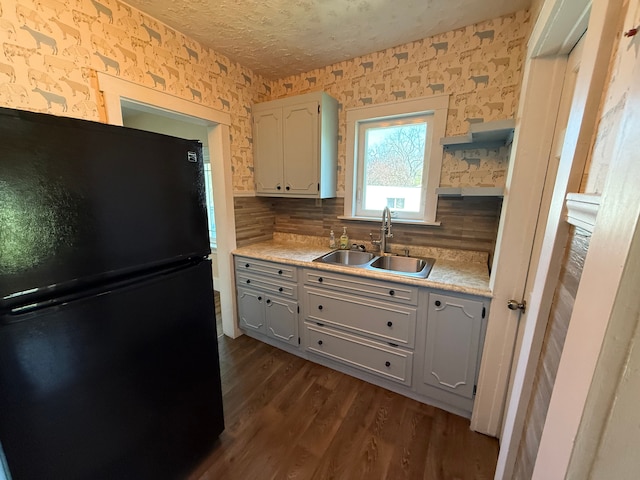 kitchen featuring freestanding refrigerator, light countertops, a sink, dark wood finished floors, and backsplash
