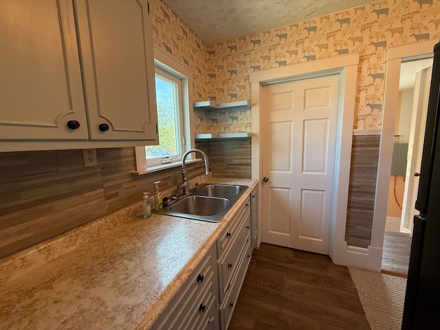 kitchen featuring tasteful backsplash, a sink, light countertops, dark wood-style floors, and wallpapered walls