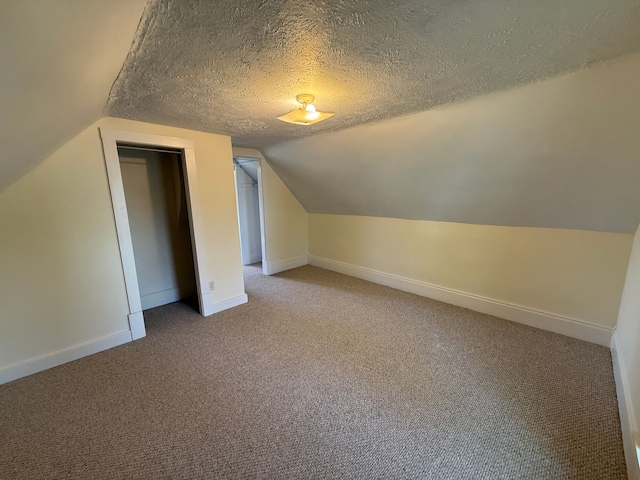 bonus room featuring baseboards, a textured ceiling, carpet floors, and lofted ceiling