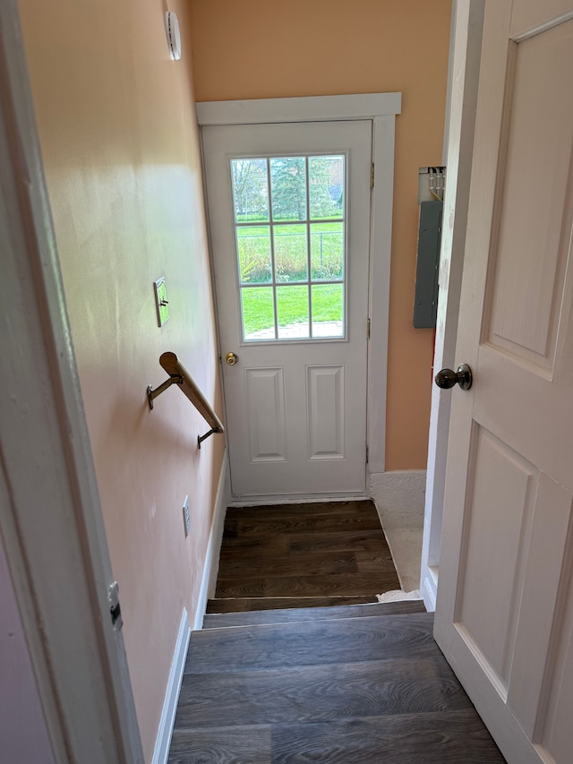 doorway with baseboards, electric panel, and wood finished floors