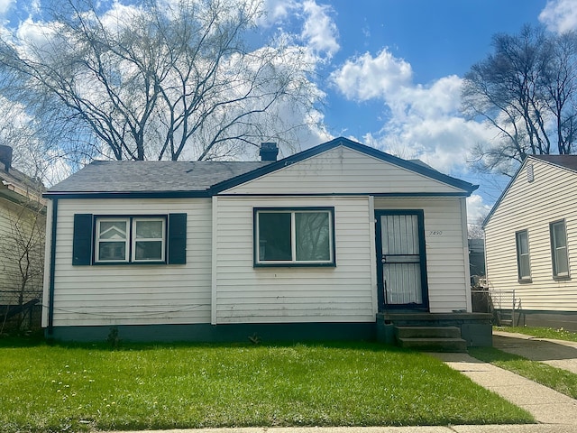 view of front facade with entry steps, a chimney, and a front yard