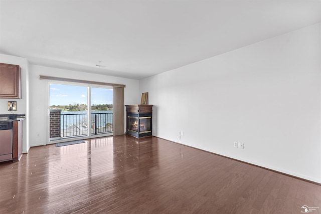 unfurnished living room featuring baseboards, a fireplace, and dark wood-style floors