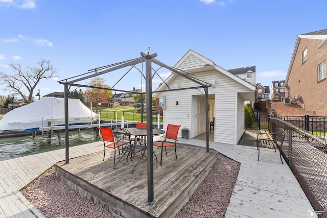 wooden deck featuring fence, boat lift, a dock, a residential view, and outdoor dining space