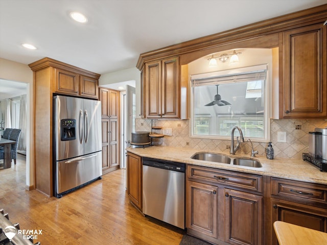 kitchen with a sink, light wood finished floors, tasteful backsplash, and stainless steel appliances