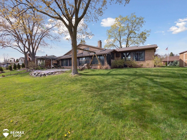 back of property featuring a yard, a patio, and a chimney