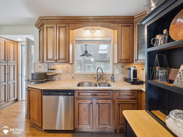 kitchen with stainless steel dishwasher, brown cabinets, a sink, and tasteful backsplash