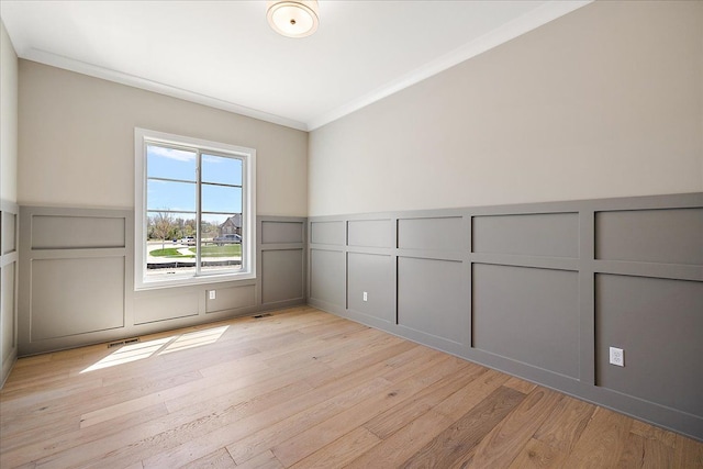 692 Westlake Ave, Oxford, MI 48371 - spare room with visible vents, crown molding, wainscoting, a decorative wall, and light wood-style flooring