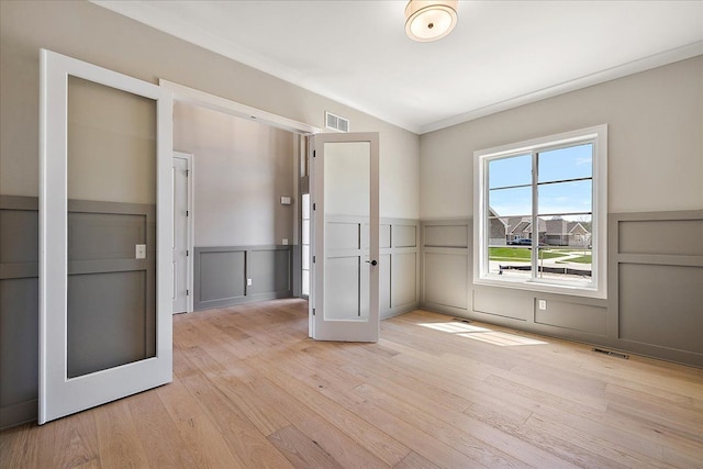692 Westlake Ave, Oxford, MI 48371 - unfurnished room featuring a decorative wall, visible vents, light wood finished floors, and a wainscoted wall