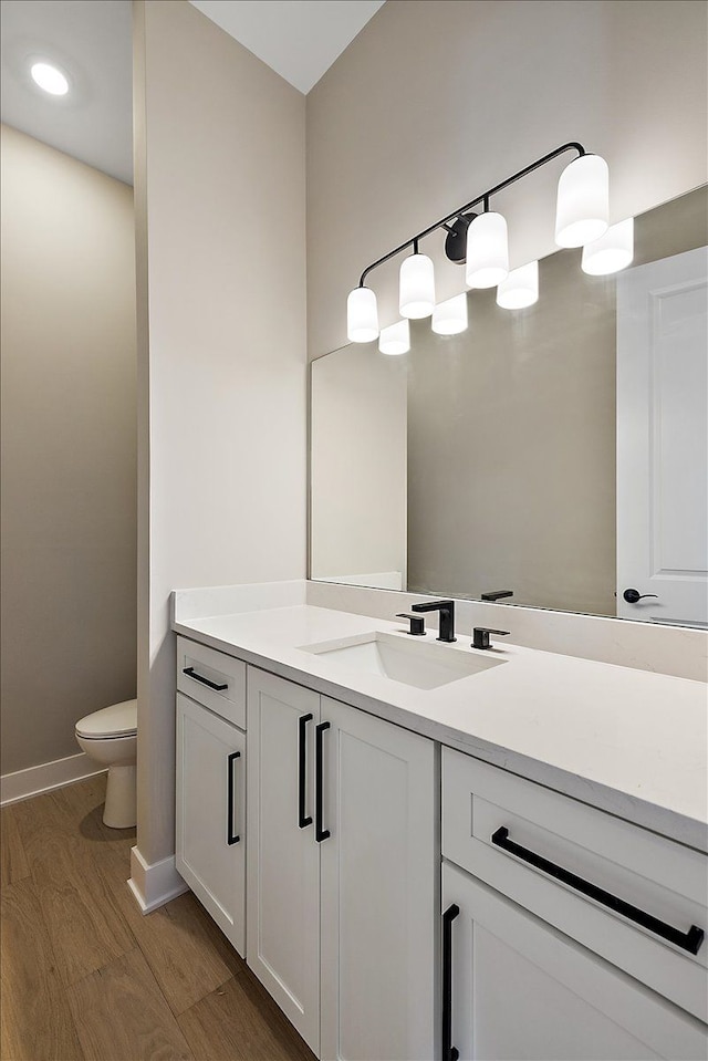 692 Westlake Ave, Oxford, MI 48371 - bathroom featuring wood finished floors, vanity, baseboards, toilet, and recessed lighting