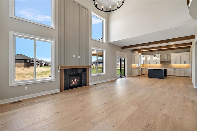 692 Westlake Ave, Oxford, MI 48371 - unfurnished living room with an inviting chandelier, a tile fireplace, visible vents, and a towering ceiling