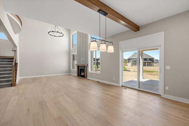 692 Westlake Ave, Oxford, MI 48371 - unfurnished living room featuring an inviting chandelier, light wood finished floors, beam ceiling, and stairway