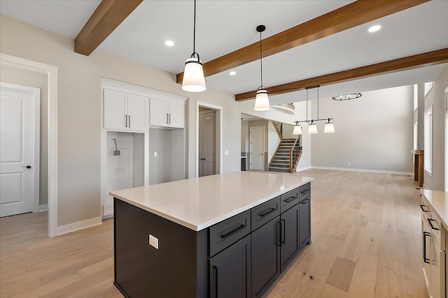 692 Westlake Ave, Oxford, MI 48371 - kitchen with beamed ceiling, baseboards, light wood-type flooring, light countertops, and white cabinetry