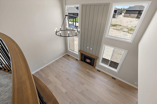 692 Westlake Ave, Oxford, MI 48371 - unfurnished living room featuring visible vents, wood finished floors, baseboards, a warm lit fireplace, and a chandelier