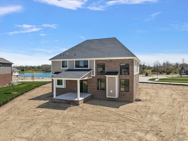 692 Westlake Ave, Oxford, MI 48371 - back of house with brick siding, a shingled roof, a water view, and a patio
