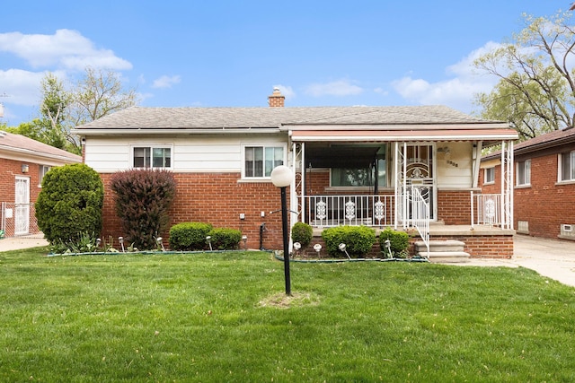 view of front facade featuring brick siding, a chimney, a front yard, and a porch