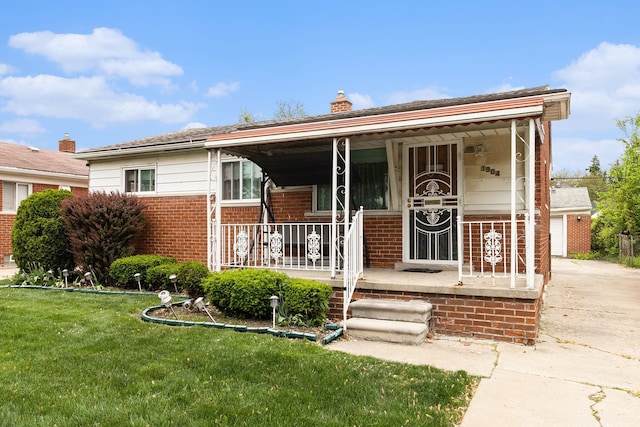 view of front of property featuring brick siding, a porch, a chimney, a front lawn, and driveway