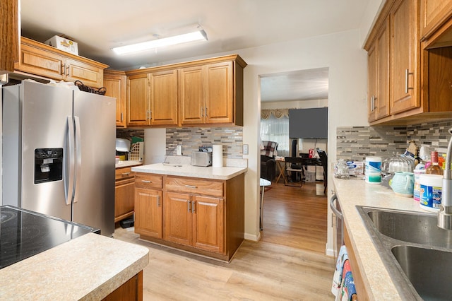 kitchen featuring stainless steel refrigerator with ice dispenser, backsplash, light wood-style flooring, and light countertops