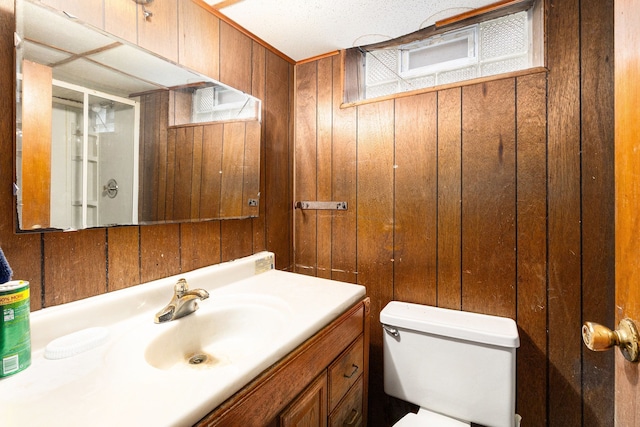 bathroom with wooden walls, vanity, toilet, and a shower